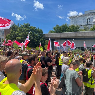 Beschäftigte der Uniklinik Tübingen stehen teils in leuchtenden ver.di-Westen beim Warnstreik.