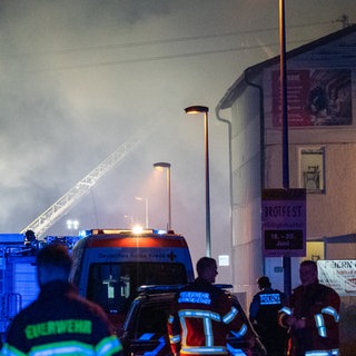 Einsatzkräfte der Feuerwehr löschen den Brand in Neufra. Die Luft ist voller Rauch. Flammen von Transporter griffen auf Industriehalle über.