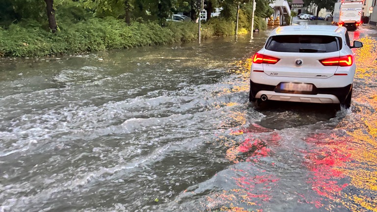 In der Reutlinger Innenstadt fährt ein Auto auf einer überschwemmten Straße.