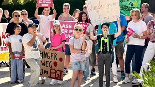 Schüler und Eltern halten Plakate nach oben. Sie stehen vor der Festhalle in Albstadt-Ebingen und protestieren gegen die Schließung des Progymnasiums.