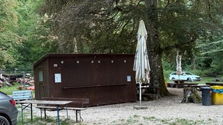 Eine Hütte steht auf einem Waldgrundstück beim Bad Uracher Wasserfall. Im Hintergrund ist Schutt von dem abgebrannten früheren Kiosk.
