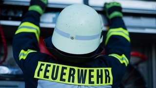 Ein Feuerwehrmann holt Equipment aus einem Einsatzfahrzeug (Symbolbild). In Reutlingen hat ein 12-Jähriger durch Zündelei eine Hecke in Brand gesetzt. 
