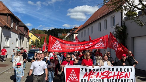 Menschen mit roten Plakaten der IG Metall ziehen durch Münsingen. Der Maschinenherstellers Walter will Stellen streichen.