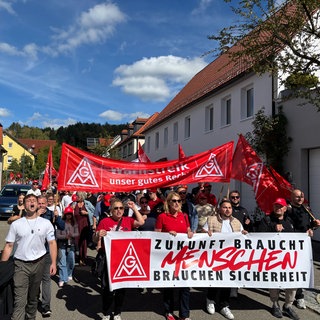 Menschen mit roten Plakaten der IG Metall ziehen durch Münsingen. Der Maschinenherstellers Walter will Stellen streichen.