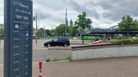 Eine Säule in Freiburg, die die Fahrradfahrenden zählt. Im Hintergrund ein Bus und Autos. 