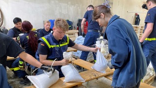 Ehrenamtliche befüllen und verladen tausende Sansdsäcke. 