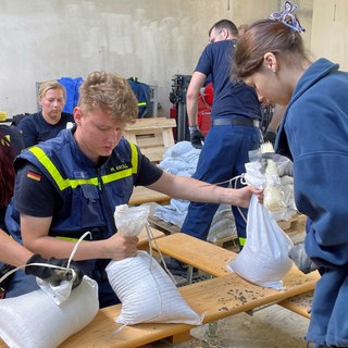 Ehrenamtliche befüllen und verladen tausende Sansdsäcke. 