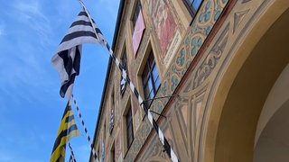 eine schwarz-gelbe und eine scharz-weiße Fahne wehen am historischen Ulmer Rathaus. Dort wurden am Montag die Pläne für die Schwörfeierlichkeiten vorgestellt.