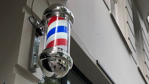 Barbierpfosten mit weiß-rot-blauen Streifen: Die typischen Hinweiszeichen auf Barbershops sind vor allem in den USA weit verbreitet und halten auch hierzulande immer mehr Einzug. 