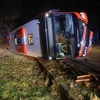 Der umgekippte Linienbus liegt auf der Straße zwischen Blaubeuren und Blaustein. Davor steht ein Feuerwehrmann. 
