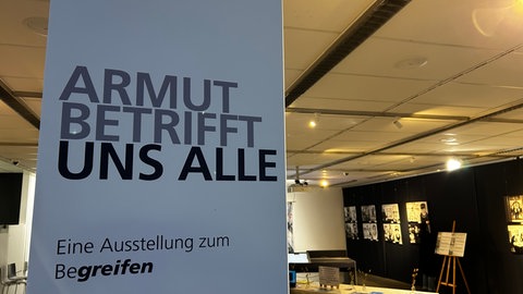 Auf einem Aufsteller ist der Ausstelltungstitel: "Armut betrifft uns alle" zu lesen, organisiert von der Stadt Ulm, der Vesperkiche und der Diakonie Ulm Alb-Donau ist im m25 in Ulm vom 16. Januar bis zum 30. März zu sehen.