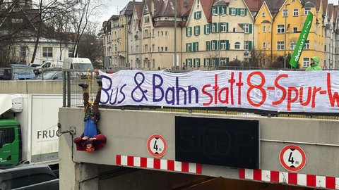 Ein Mann hängt bei einer Protestaktion am Montag kopfüber neben einem Transparent an einer Tunneeinfahrt der B10 in Ulm. Umweltaktivisten wollen mit der erneuten Aktion ihre Forderungen bekräftigen.