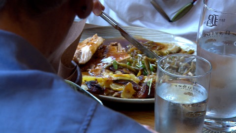 Ein Teller mit einem Gericht, zwei Menschen sitzen daneben