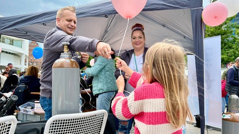 Ein Mädchen bekommt auf dem Deutschen Musikfest einen Ballon überreicht. 