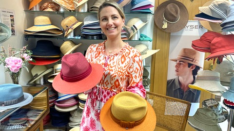 Orange und gelb - Juliane Fischer mit Hüten in der Hand. Im Hutalon der Oma mit Atelier in Schechingen (Ostalbkreis) werden seit Generationen Hüte herstellt.