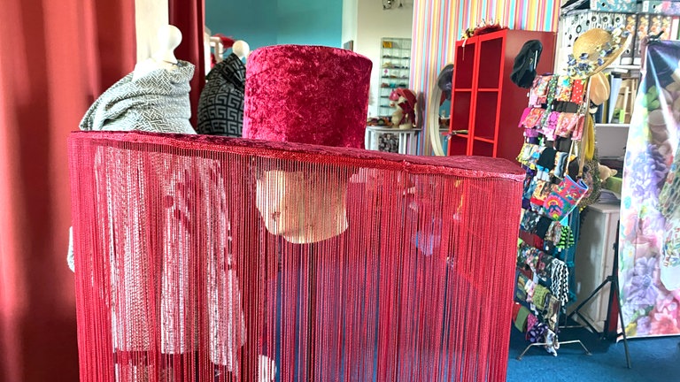 Purpurrot und riesig - ein 70 Zentimeter breiter Hut mit bodenlangen Fransen. Er wurde im Ulmer Atelier für die Aufführung einer Tanzcompagnie gestaltet. 