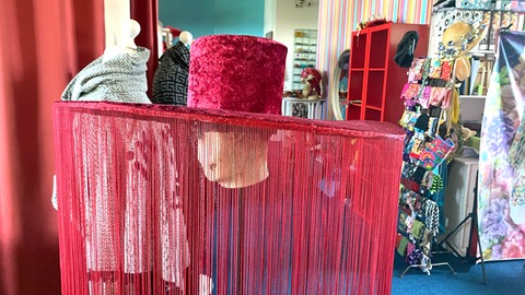 Purpurrot und riesig - ein 70 Zentimeter breiter Hut mit bodenlangen Fransen. Er wurde im Ulmer Atelier für die Aufführung einer Tanzcompagnie gestaltet. 