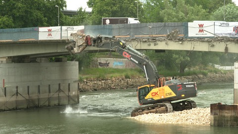 Ein Riesenbagger trägt Teile der Gänstorbrücke zwischen Ulm und Neu-Ulm von der Donau aus ab.
