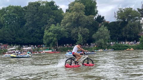 Ein Mann ist am Schwörmontag mit einem wasserfähigen Fahrrad unterwegs.