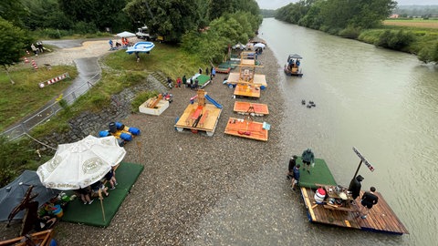 Mehrere Floße auf einem einem kleinen Steinstrand an der Donau. Die wilden Nabader warten nun, bis der große Wasserumzug losgeht. 