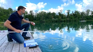 Jens Eberhard vom Gesundheitsamt Alb-Donau-Kreis entnimmt aus einem  Badesee eine Wasserprobe: Die Wasserqualität in EU-Badeseen wird während der Badesaison regelmäßig kontrolliert. 