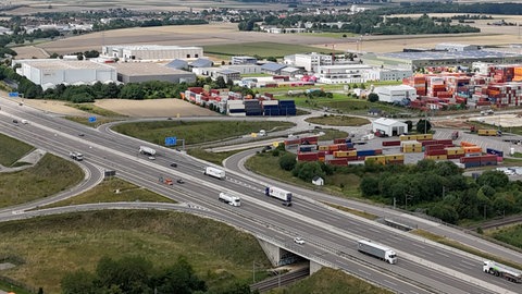 Noch gibt es links des Kreisverkehrs nichts außer Feld und Steine. Doch auf der Fläche zwischen dem Kreisverkehr und der A8 soll eine Art Universal-Tankstelle entstehen. Dort sollen Lkw, Busse und Autos tanken können - sowohl Sprit, als auch Strom und Wasserstoff.