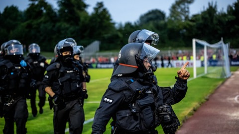 Einsatzkräfte der Polizei in schwarzer Uniform und mit schwarzen Helmen. Nach dem DFB-Pokalspiel Illertissen gegen Nürnberg gibt es eine Schlägerei unter Fans. Die Polizei greift mit großem Aufgebot ein.