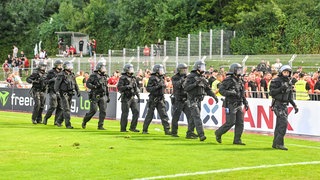 Einsatzkräfte der Polizei in schwarzer Uniform und mit schwarzen Helmen. Nach dem DFB-Pokalspiel Illertissen gegen Nürnberg gibt es eine Schlägerei unter Fans. Die Polizei greift mit großem Aufgebot ein.