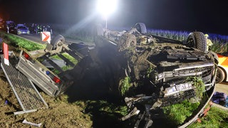 Ein weißer Kleintransporter liegt nach einem Unfall samt Anhänger abseits der Straße auf dem Dach: Nach dem Überschlag mit seinem Gespann starb der Fahrer noch an der Unfallstelle nahe Ichenhausen.