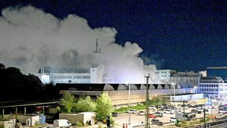 Rauch über einer Lagerhalle: Mehr als drei Monate nach dem Brand in der Außenstelle des Ulmer Theaters hat die Polizei nun einen Tatverdächtigen festgenommen. Hinweise auf Brandstiftung gab es schon länger. (Archivbild)