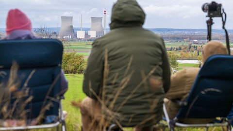 Schaulustige warten auf einem Hügel auf die Sprengung der beiden Kühltürme des stillgelegten Kernkraftwerks Gundremmingen. 