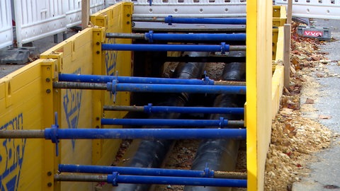 Eine aufgerissene Straße mit vielen Rohren. Hier werden Fernwärmeleitungen verlegt, um die Wärmewende voranzutrieben. Bis zu fünf Kilometer pro Jahr baut die Fernwärme Ulm GmbH aus.