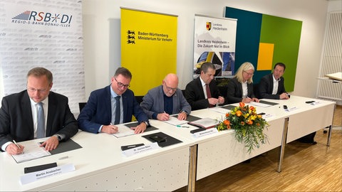 Verkehrsminister Winfried Hermann (Grüne) in der Mitte der Landräte und des Ulmer OBs. Die Finanzierung der Planungskosten zum Ausbau der Brenzbahn steht. 