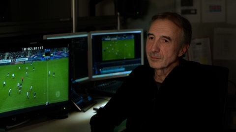 Wolfgang Bunz aus Ulm vor zwei Bildschirmen auf dem gerade eine Szene aus dem Fußballspiel zwischen Frankreich und Deutschland im Jahr 2015 läuft. Das Stadion in Paris war auch ein Ziel bei den wohl größten Terroranschlägen in Frankreich.