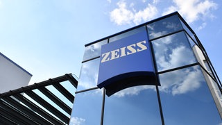 Die Konzernzentrale von Zeiss in Oberkochen mit dem Logo - eine glänzende Fassadel in der sich Himmel und Wolken spiegeln