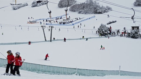 Zwei Skifahrer im Schlepplift: Schnee in Westerheim und Betrieb auf der Piste.