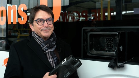 Horst Bottenschein steht vor einem Bus. Er zieht bislang ein positives Fazit für seine neuen E-Busse aus China.