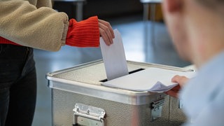 Eine Frau steckt ihren Stimmzettel in eine Wahlurne. Das Projekt Wahlwatching in Ulm: Schüler können als Wahlbeobachter lernen, wie eine Landtagswahl funktioniert