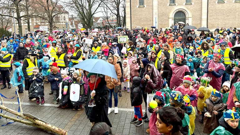 Bunte Faschingsmenge feiert im Regen vor dem Rathaus in Wasseralfingen.