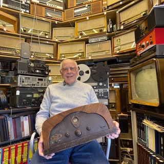 Werner Hauf in seinem Museum für Radios: 1.300 historische Geräte hat er mittlerweile gesammelt. Das Radio auf seinem Schoß ist sein erstes in der Sammlung, ein Lomophon Gloria 33.