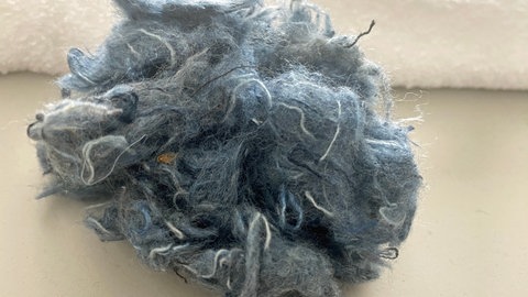 Sieht aus wie der Inhalt eines Staubsaugerbeutels - bevor aus ausgemusterten T-Shirts oder Bettlaken Recycling-Garn entstehen kann, müssen die Alttextilien zunächst in ihre Einzelfasern zerlegt und entsprechend aufbereitet werden.