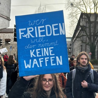 Eine Schülerin hält ein blaues Plakat mit der Aufschrift "Wer Frieden will, nimmt keine Waffen" in die Luft. Junge Leute demonstrieren in ganz BW gegen die Wehrdienstpläne der Bundesregierung. Aufgerufen hatte das junge Bündnis "Schulstreik gegen Wehrpflicht". (Archivbild)