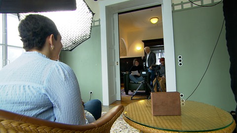 Die Patientin sitzt gegenüber dem Drehteam und wartet auf den Beginn der Aufnahme.
