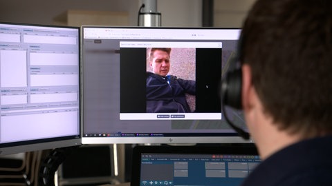 Mann sitzt vor Monitoren