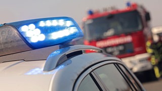 Blaulicht eines Polizeiautos und im Hintergrund die Feuerwehr. Ein Arbeiter ist in Blaubeuren unter einer tonnenschweren Wand begraben worden. (Symbolbild)