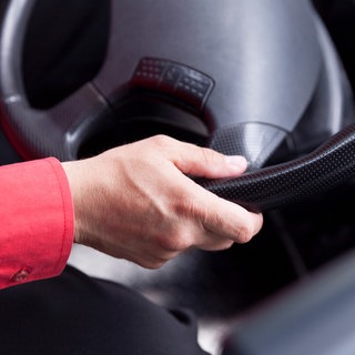 Ein Busfahrer hält ein Lenkrad fest. In Schwäbisch Gmünd-Hussenhofen wurde laut Polizei ein Busfahrer von Jugendlichen attackiert. (Symbolbild)