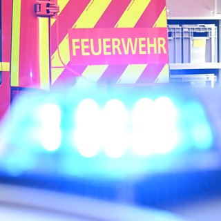 Ein Fahrzeug der Feuerwehr steht bei einem Einsatz, während im Vordergrund das Blaulicht eines Polizeifahrzeugs zu sehen ist. In einer Fabrik in Giengen an der Brenz ist am Dienstagmittag Quecksilber ausgetreten. (Symbolbild)