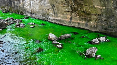 Ein Fluss mit Steinen unter einer Brücke, das Wasser leuchtet grün: Anfang April leuchtete der Josefsbach für kurze Zeit giftgrün. Gesucht wird nach einem Unbekannten, eine Flüssigkeit hineingeschüttet haben soll.