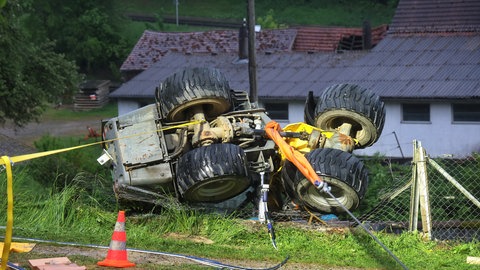Eine Baumaschine liegt mit allen vier Rädern oben vor einem Haus: In Roggenburg (Kreis Neu-Ulm) ist ein Mann am Sonntag ums Leben gekommen, als er unter einen Radlader geriet. Er hatte einen steilen Abhang begradigen wollen. Das Fahrzeug kippte um, der Mann wurde von der Maschine erschlagen.