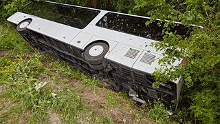 Ein weißer Bus liegt auf der Seite in einem Graben: Bei Aalen ist ein Omnibus umgekippt